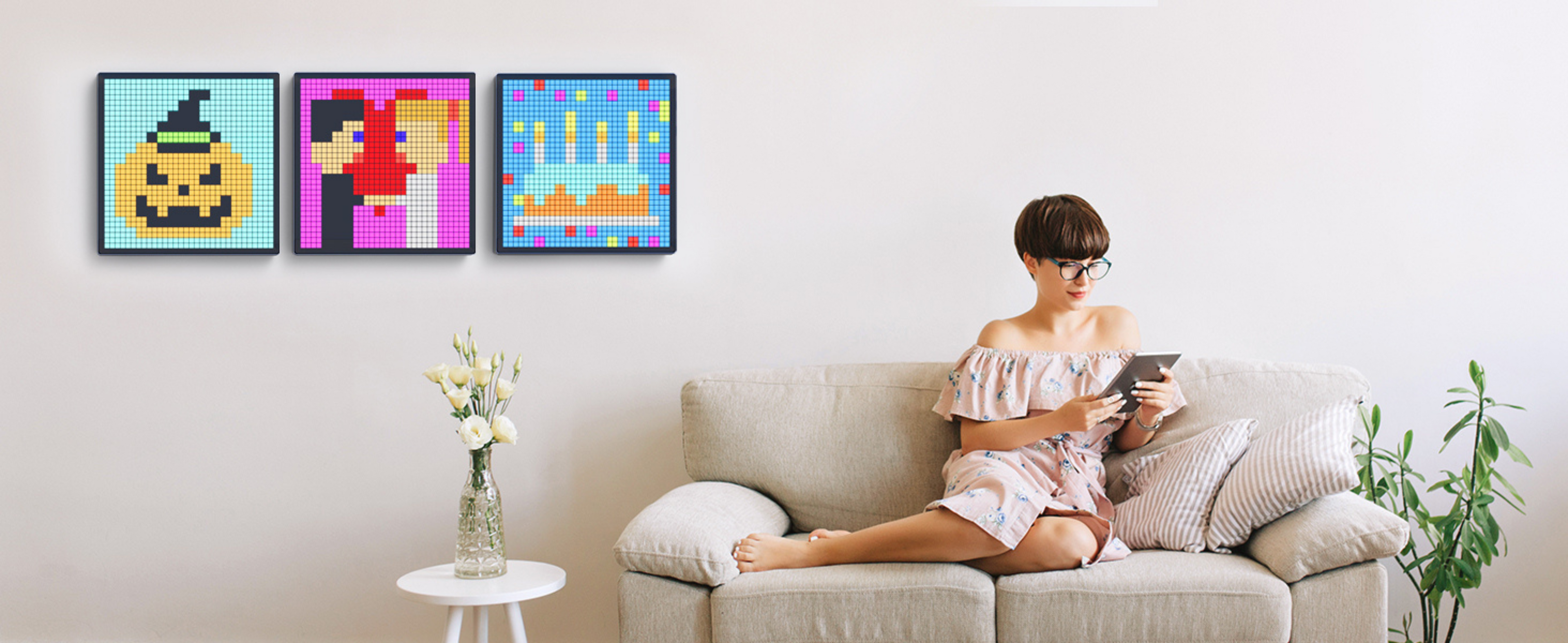Woman sitting on a couch in a living room with colorful Apex pixel display art frames on the wall , Apex Pixel Display in India for gaming setups, music sync, and home déco